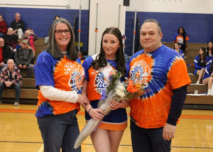 Family poses with student-athlete in gymnasium