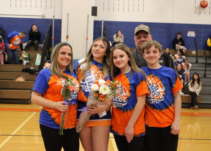 Family poses with student-athlete in gymnasium