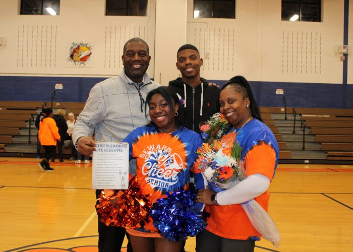 Family poses with student-athlete in gymnasium