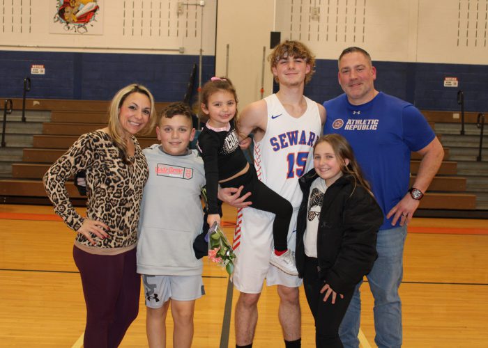 Family poses with student-athlete in gymnasium