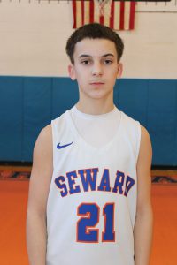 Grey Whitmore stands in the gym in his basketball jersey