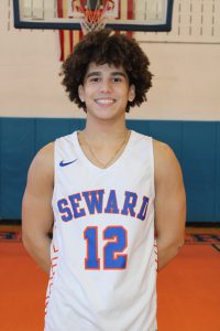Basketball player Nick Perez smiles for the camera in front of the basketball hoop