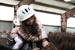 Pre-K student pets horse while mounted at Winslow field trip