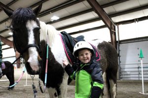 pre-K student smiles after dismounting from his horse at Winslow field trip