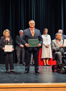 BOE President poses on stage with award