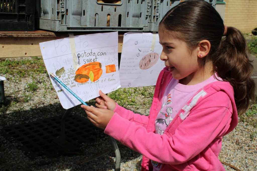Student pointing to drawings of vegetables 