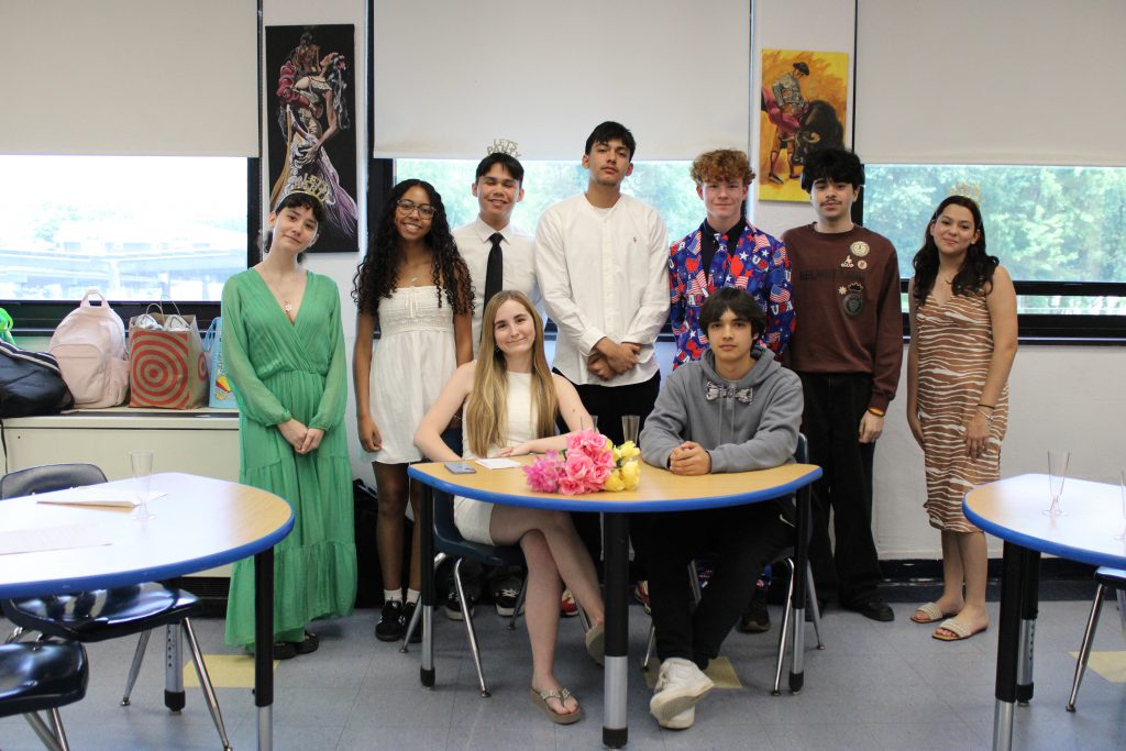 Students pose in a group behind table